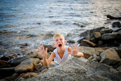 Portrait of boy on rock at sea shore