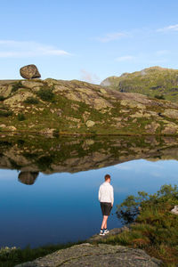 Rear view of man standing on rock against sky
