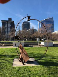 Park by buildings in city against sky