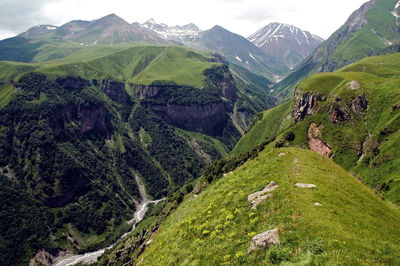 Scenic view of green landscape and mountains against sky