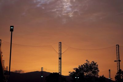Silhouette trees and electricity pylon against sky during sunset