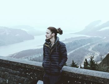 Young man standing on mountain against sky