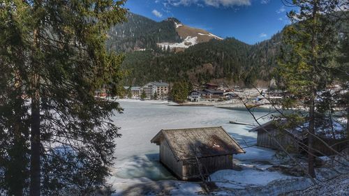 Scenic view of lake by buildings against sky during winter