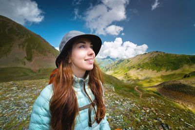 Portrait of a smiling woman resting during a mountain hike. a woman with a backpack enjoys the view