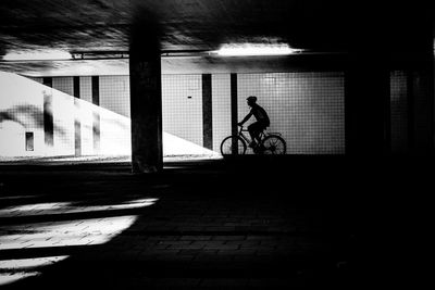 Silhouette man riding bicycle on city