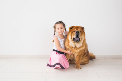 Portrait of cute girl with dog sitting on floor