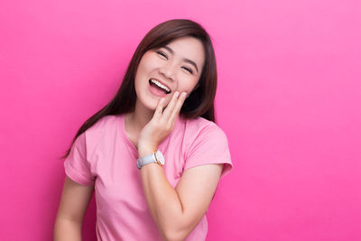 Portrait of a smiling young woman against pink background