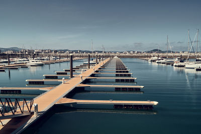 Boats moored at harbor against sky