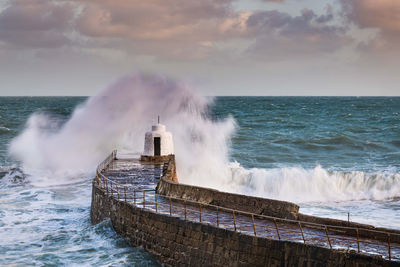 Waves splashing on sea against sky