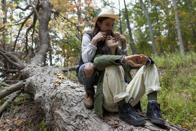 Rear view of couple sitting on bench against trees