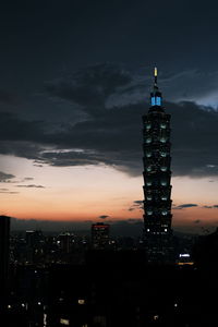 Illuminated buildings in city against sky at sunset