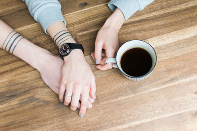 Cropped hands of man and woman holding hands by black coffee at home