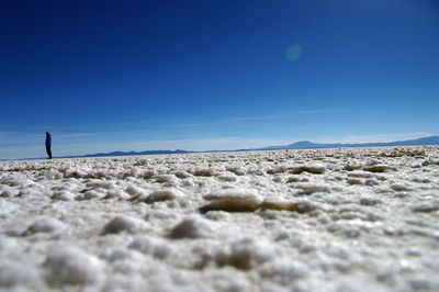 Surface level shot of woman standing on land against clear blue sky