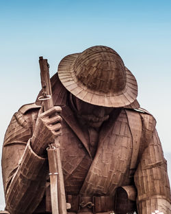 Low angle view of man standing sculpture against clear sky