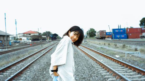Woman standing on railroad track against clear sky