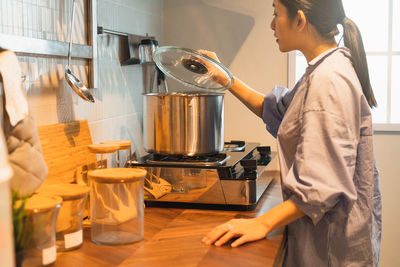 Side view of woman preparing food in kitchen at home