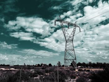 Low angle view of electricity pylon on field against sky