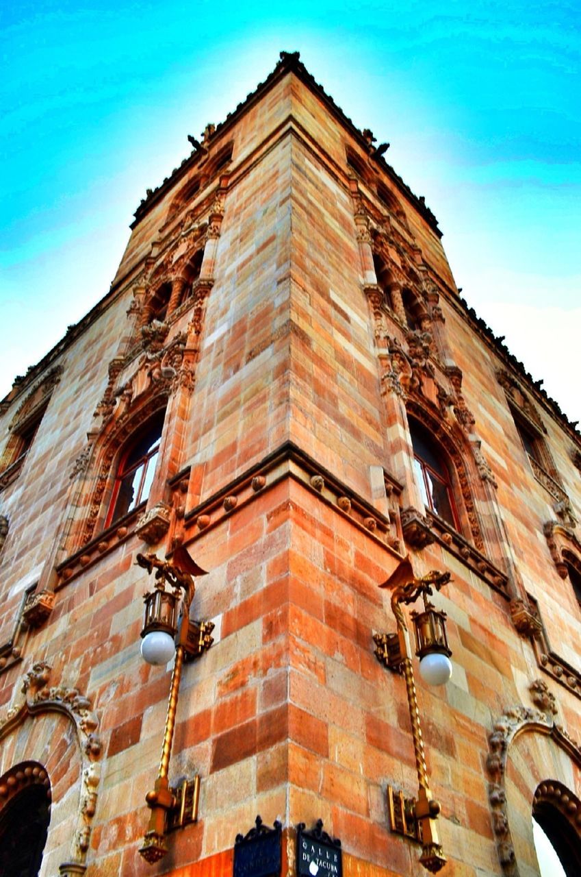 architecture, building exterior, low angle view, built structure, window, sky, building, blue, city, outdoors, no people, day, facade, residential building, old, tower, tall - high, exterior, brick wall, history