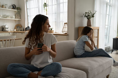 Sad offended girl child expecting attention and time from mother spending too much time on phone