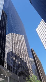 Low angle view of skyscrapers against blue sky