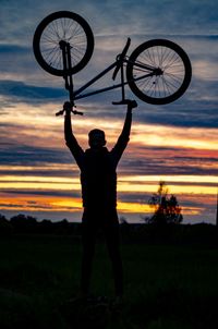 Silhouette man standing on field against sky during sunset