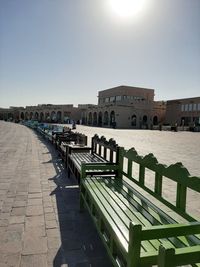 Empty footpath by buildings against clear sky