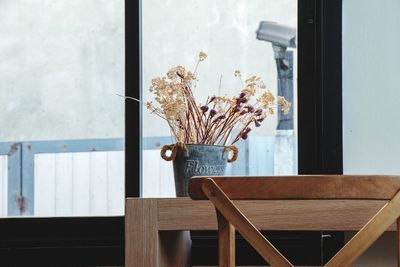 Flower vase on table against window