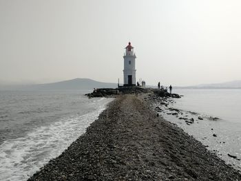 Lighthouse by the sea against the foggy sky
