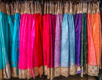 Full frame shot of multi colored womenswear hanging on rack in store