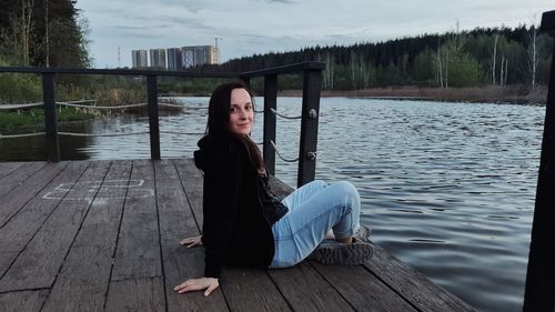 Portrait of woman sitting on pier over lake