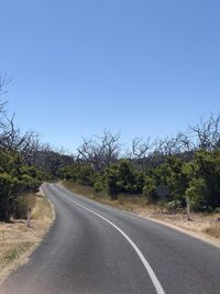 Road by trees against clear sky