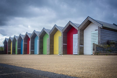 Row of colourful hut on beach front against sky