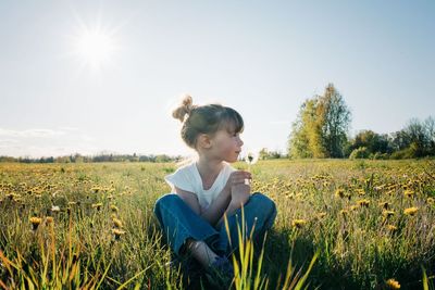 Young girl sat in a peaceful field of flowers in summer