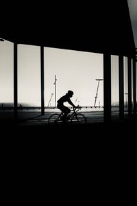 Silhouette man riding bicycle against sky