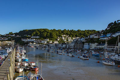 Boats moored at harbor against clear blue sky