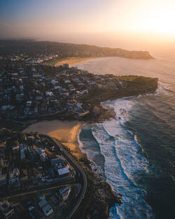 High angle view of buildings by sea against sky during sunset