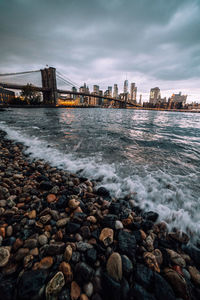 View of city at waterfront against cloudy sky