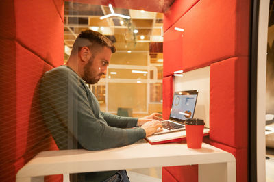 Side view of young man using digital tablet while sitting at home