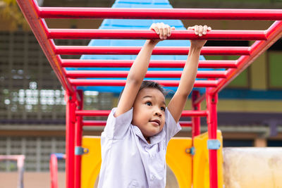 Portrait of happy girl with arms raised against blurred background