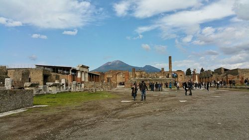 Tourists in front of building against cloudy sky