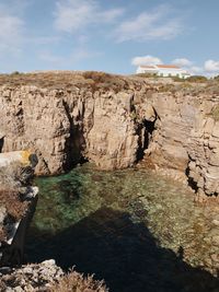 View of rock formation on shore against sky