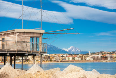 Sailboats on beach by buildings against sky