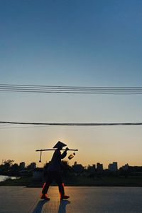 Rear view of silhouette man standing in city against sky during sunset