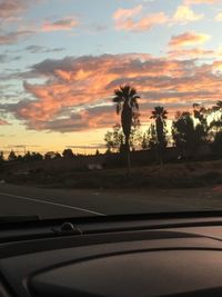 Road by trees against sky during sunset