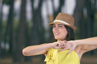 Smiling woman wearing hat against trees