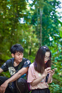 Woman using phone with boyfriend in forest