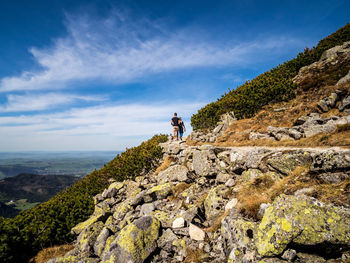 Man standing on rock against sky