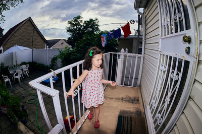 Cute young girl in a summer dress playing in a suburban backyarrd