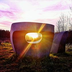 Close-up of illuminated lamp on field against sky during sunset