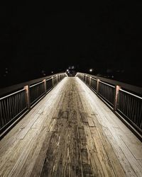 Illuminated footbridge against sky at night